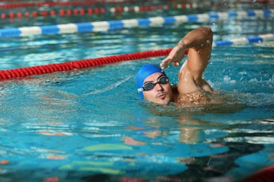 Young athletic man swimming in pool indoors