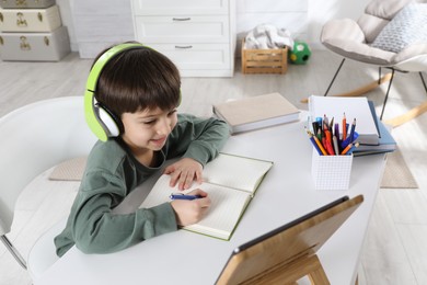 Cute little boy with modern tablet studying online at home. E-learning