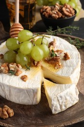 Brie cheese served with grapes, walnuts and honey on table, closeup