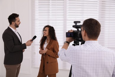 Professional journalist interviewing young African American woman indoors