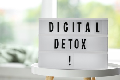 Photo of Lightbox with phrase DIGITAL DETOX on white table indoors