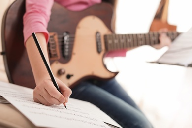 Little girl with guitar writing music notes indoors, closeup