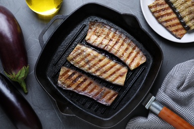 Delicious grilled eggplant slices in pan on grey table, flat lay