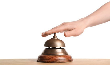 Woman ringing hotel service bell at wooden table