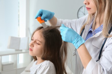 Doctor using nit comb on girl's hair in clinic. Anti lice treatment