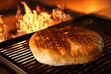 Baking pita bread on grilling grate in oven, closeup