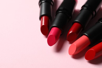 Photo of Many bright lipsticks on pink background, closeup. Space for text
