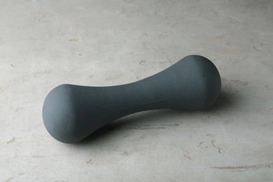 Grey rubber coated dumbbell on light table