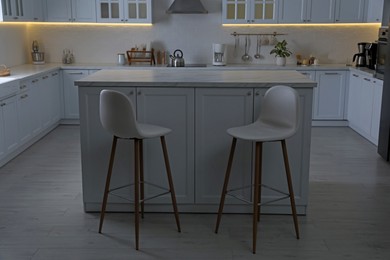 Modern kitchen interior with white marble table and stylish high chairs