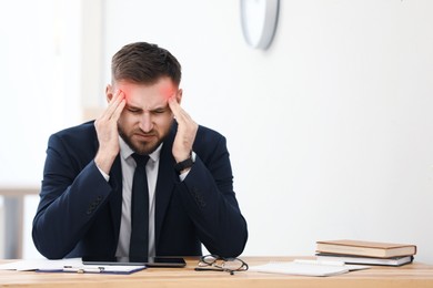 Image of Man suffering from migraine at workplace in office
