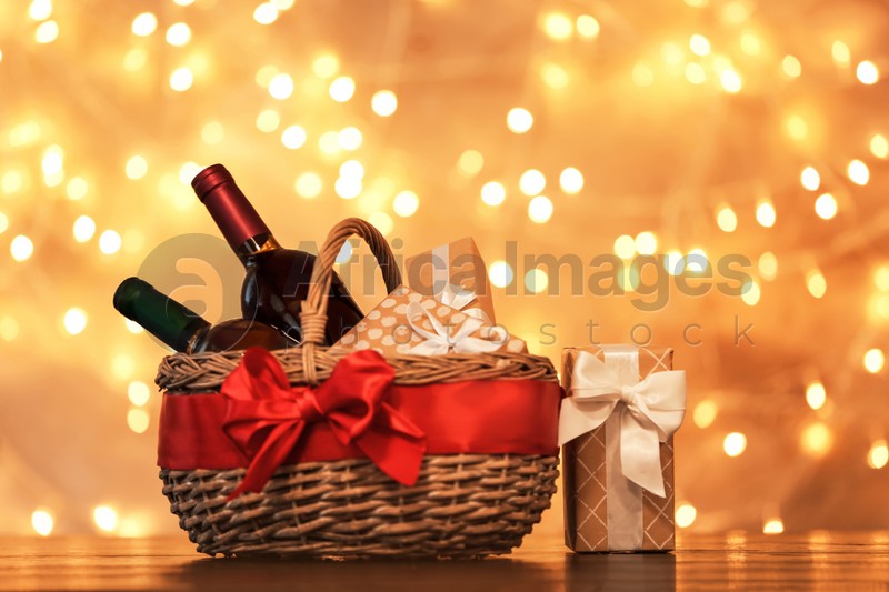 Gift basket with bottles of wine against blurred lights. Space for text