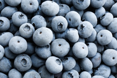 Tasty frozen blueberries as background, top view