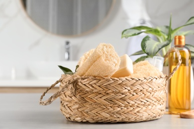 Natural loofah sponges and soap bar in wicker basket on table indoors