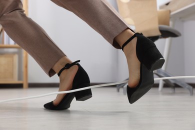 Photo of Woman tripping over cord in office, closeup