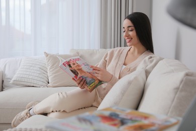 Young woman reading sports magazine on sofa at home