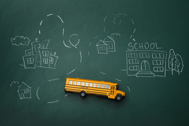 Yellow school bus and drawing on chalkboard, top view. Transport for students