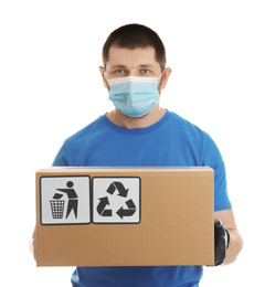 Courier in mask holding cardboard box with different packaging symbols on white background. Parcel delivery