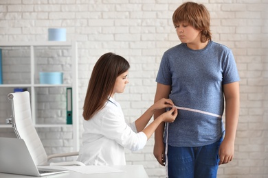 Female doctor measuring overweight boy in clinic
