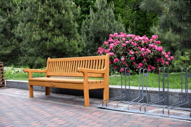 Comfortable wooden bench and bicycle parking rack in garden