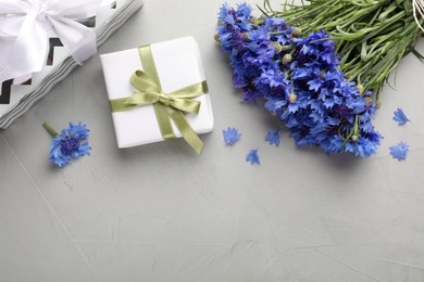 Bouquet of beautiful cornflowers and gift boxes on light table, flat lay. Space for text