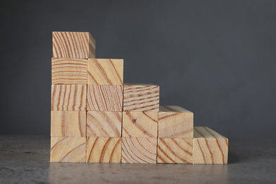 Steps made with wooden blocks on table against grey background. Career ladder