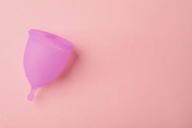 Menstrual cup on pink background, top view. Space for text