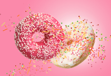 Sweet delicious donuts falling on pink background