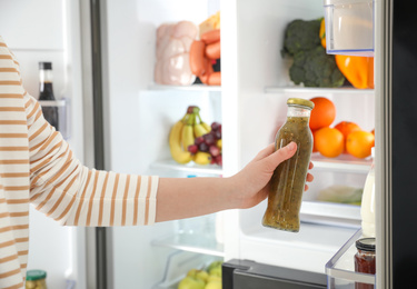 Young woman taking sauce out of refrigerator, closeup