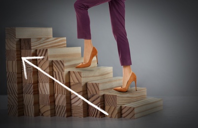 Businesswoman walking up stairs against grey background, closeup. Career ladder concept