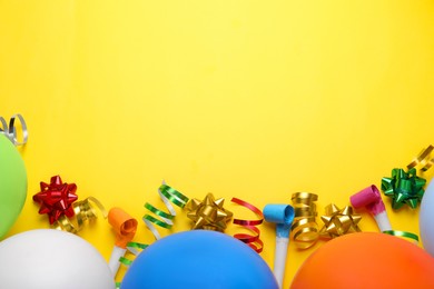 Photo of Balloons, party blowers and streamers for birthday party on yellow background, flat lay. Space for text