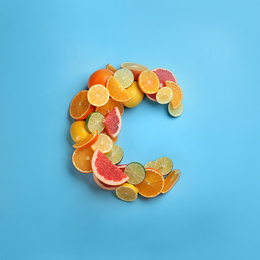 Letter C made with citrus fruits on light blue background as vitamin representation, flat lay