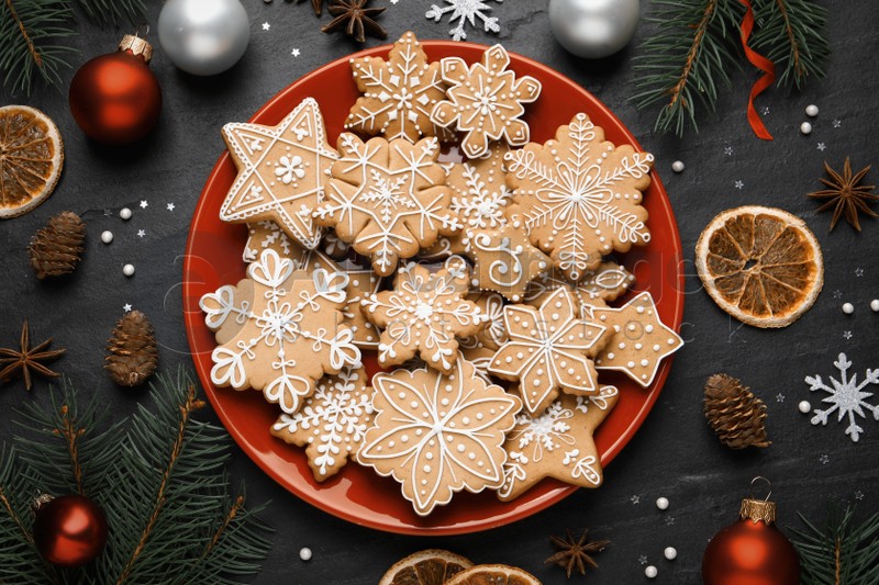 Tasty Christmas cookies, fir branches and festive decor on black table, flat lay