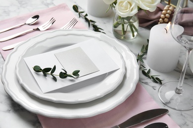 Elegant festive table setting with blank card on white marble background