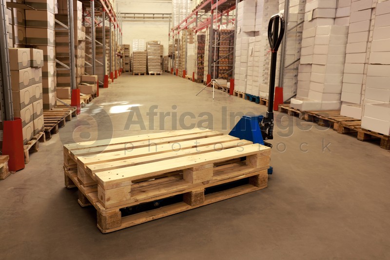 Modern manual forklift with wooden pallets in warehouse