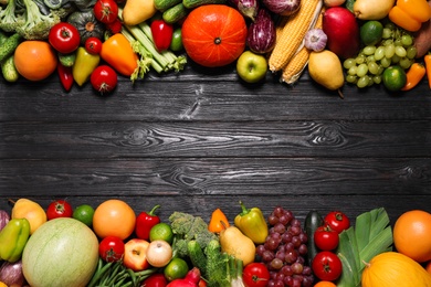 Assortment of fresh organic fruits and vegetables on black wooden table, flat lay. Space for text