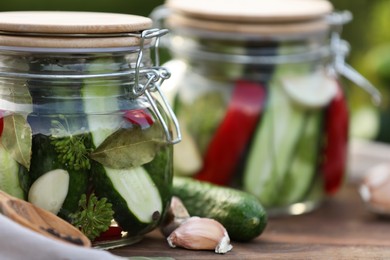 Jars of delicious pickled cucumbers on wooden table, closeup