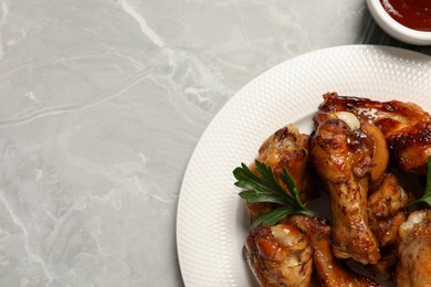 Plate with delicious fried chicken wings on light gray table, top view. Space for text
