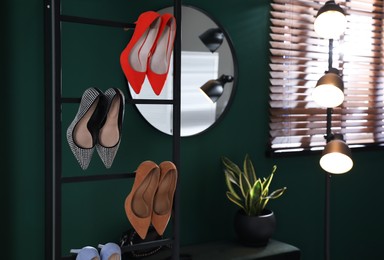 Storage rack with stylish women's shoes in hallway