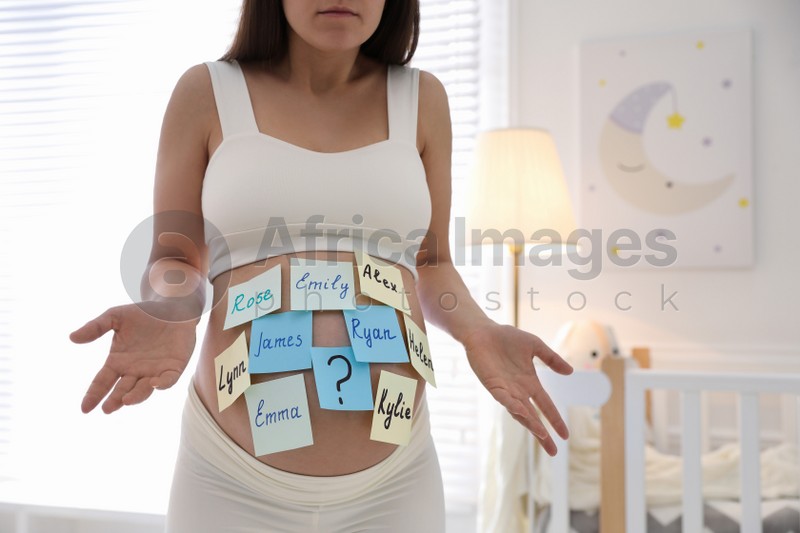 Pregnant woman with different baby names on belly at home, closeup