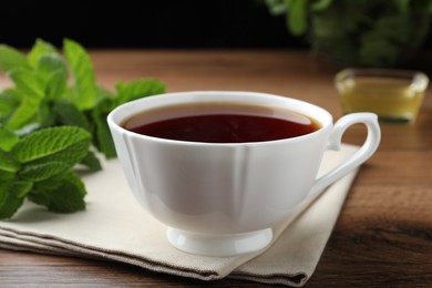 Photo of Cup of hot aromatic tea with mint on wooden table