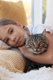 Photo of Cute little girl with her cat at home, closeup. Childhood pet