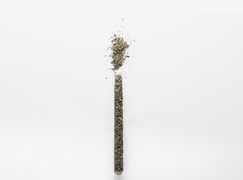 Photo of Glass tube with Italian herb mix on white background, top view