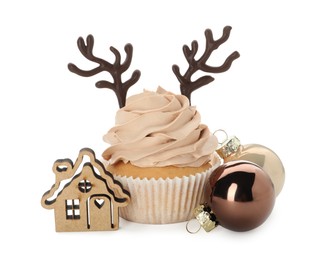 Delicious cupcake with chocolate reindeer antlers and Christmas decor on white background