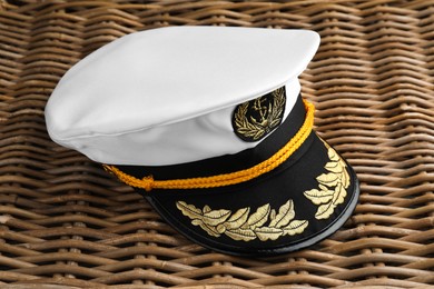 Peaked cap with accessories on wicker surface, closeup