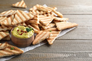 Photo of Delicious pita chips and hummus on wooden table
