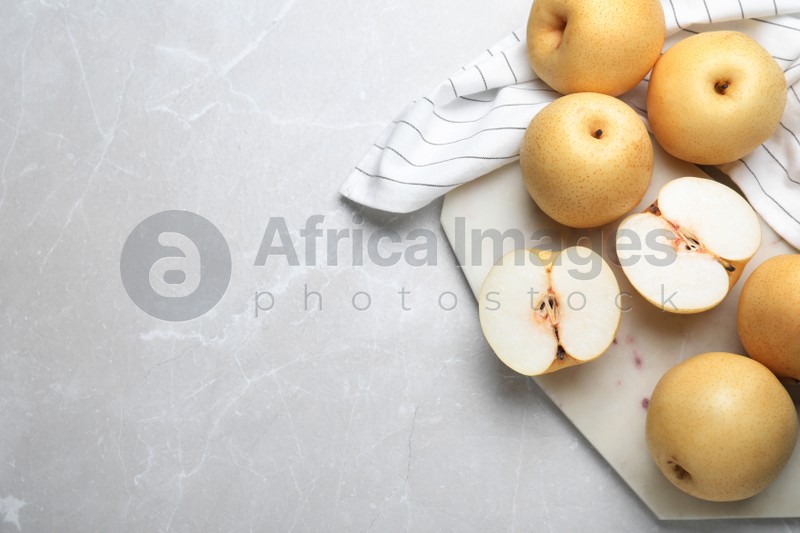 Photo of Cut and whole apple pears on light grey table, flat lay. Space for text