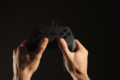 Man holding video game controller on black background, closeup