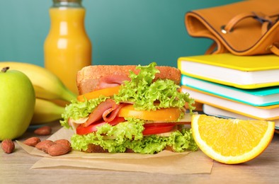 Tasty healthy food and different stationery on wooden table near green chalkboard, closeup. School lunch