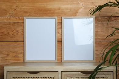 Photo of Empty frames on table near wooden wall. Mockup for design