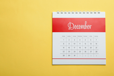 Photo of December calendar on yellow background, top view. Space for text